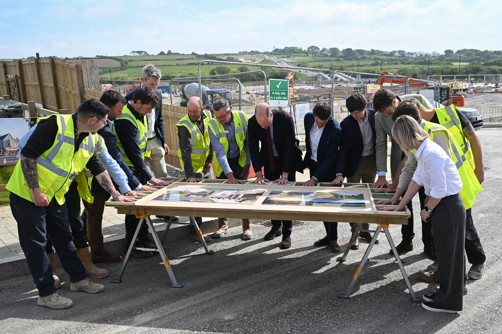 Duke Of Cornwall Several People In Yellow Vests Are Looking At Pictures On A Table