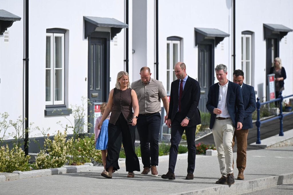Duke Of Cornwall Several People Walking Down A Sidewalk In Front Of A Row Of White Houses
