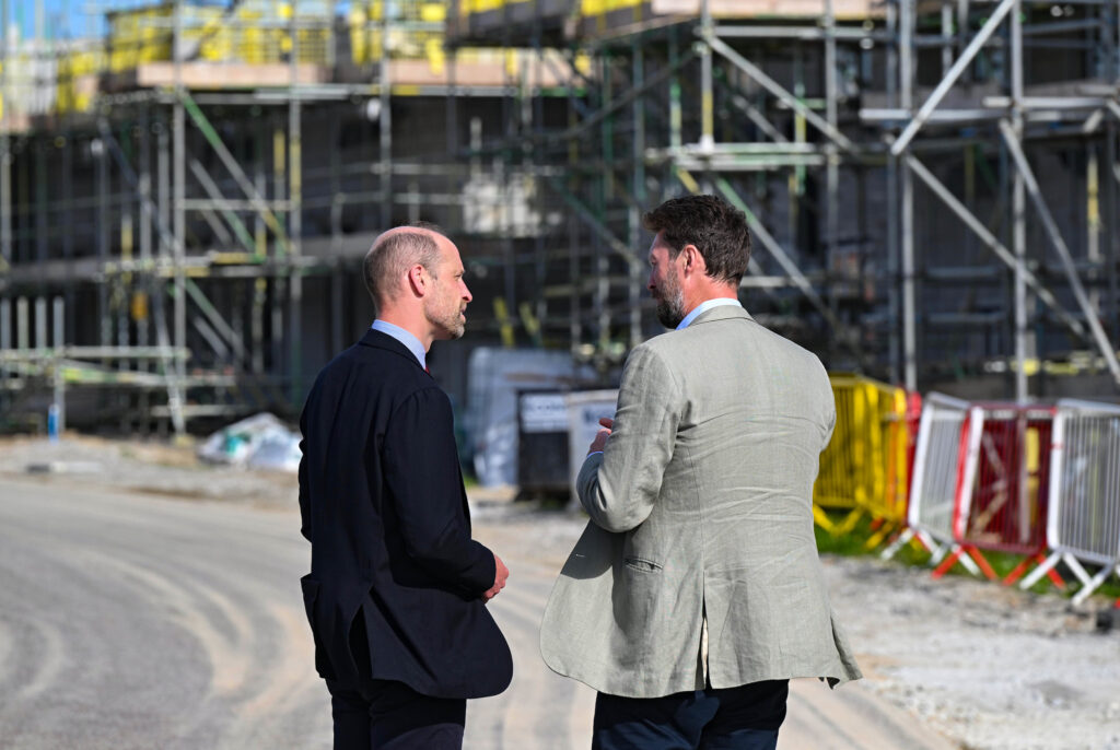 Duke Of Cornwall Two Men In Suits Talking On A Street With A Building In The Background